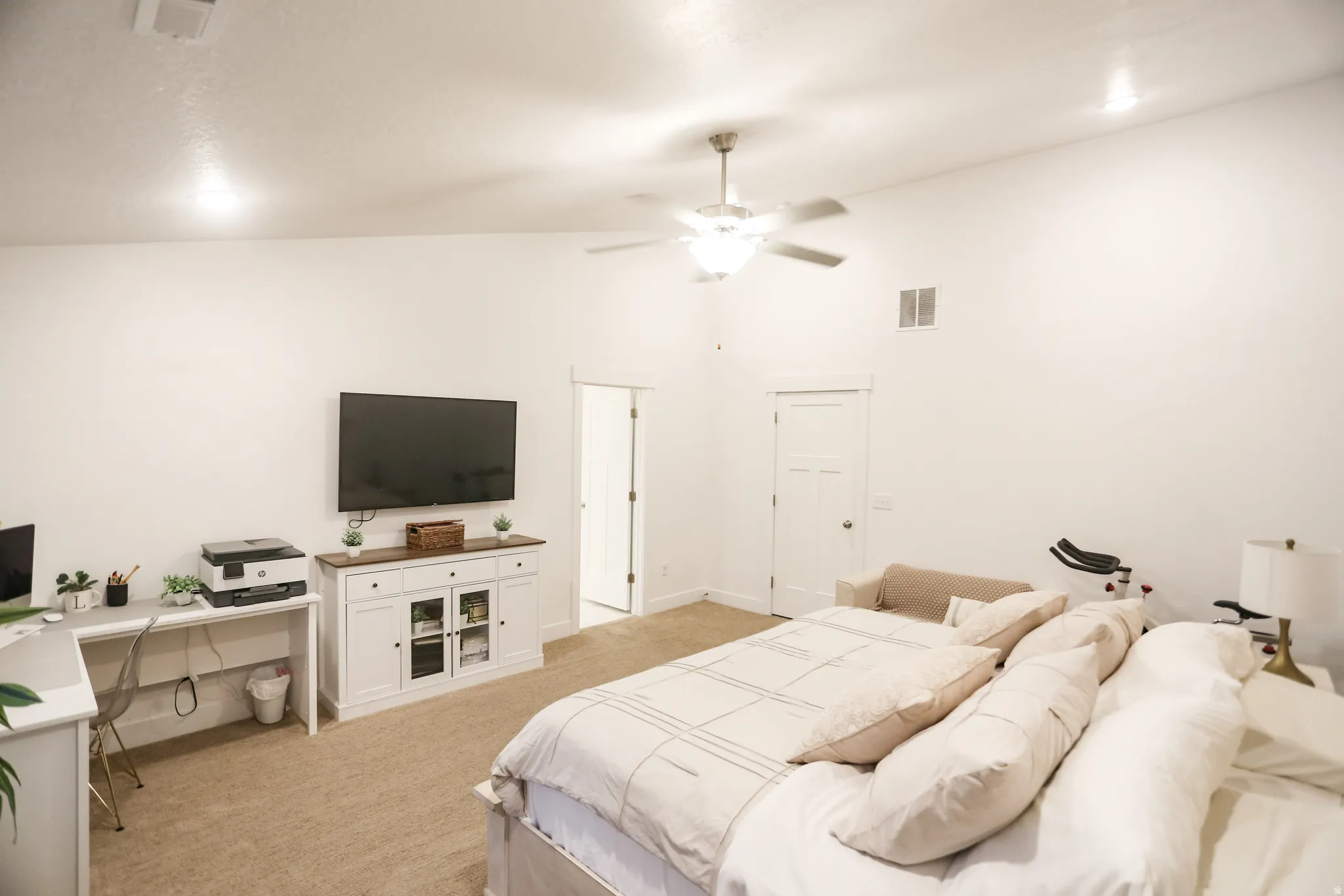 Bedroom with a desk, light colored carpet, ceiling fan, and vaulted ceiling