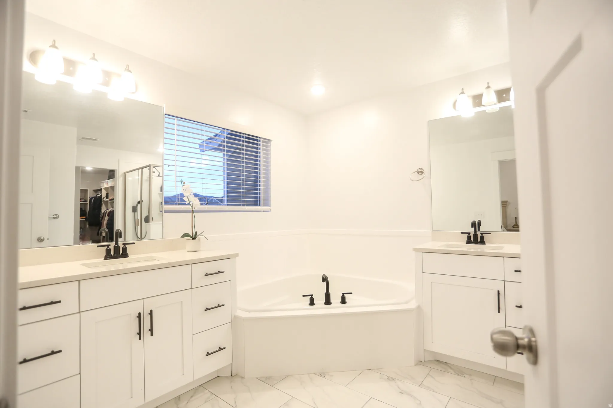 Full bathroom featuring two vanities and a garden tub
