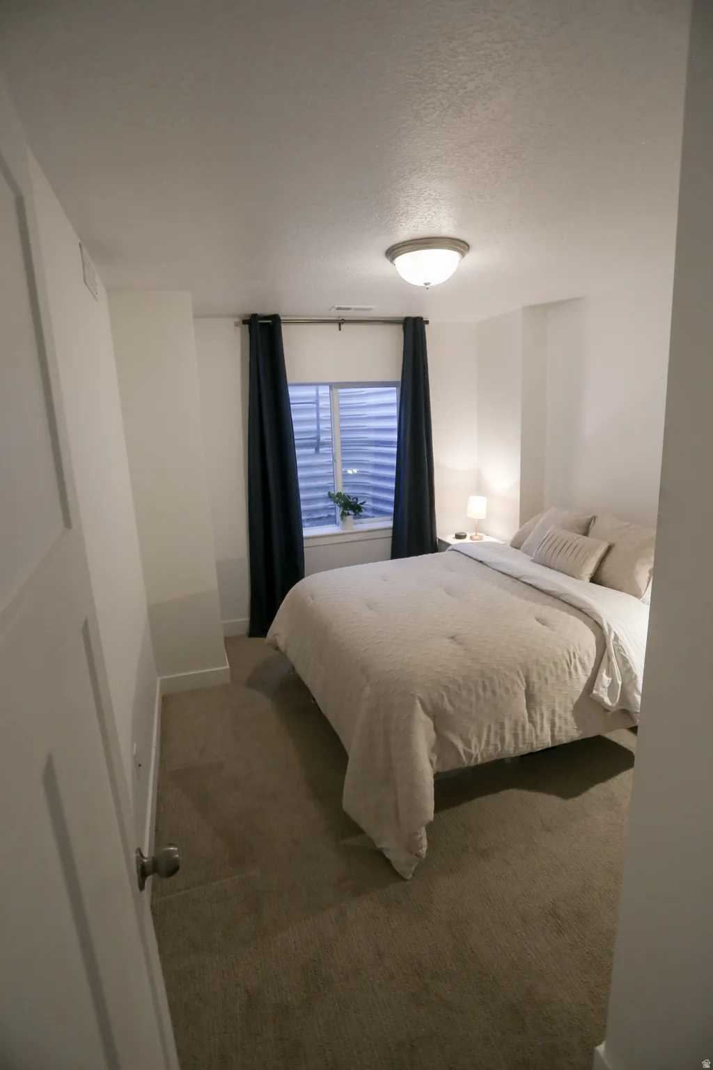 Carpeted bedroom featuring a textured ceiling and baseboards