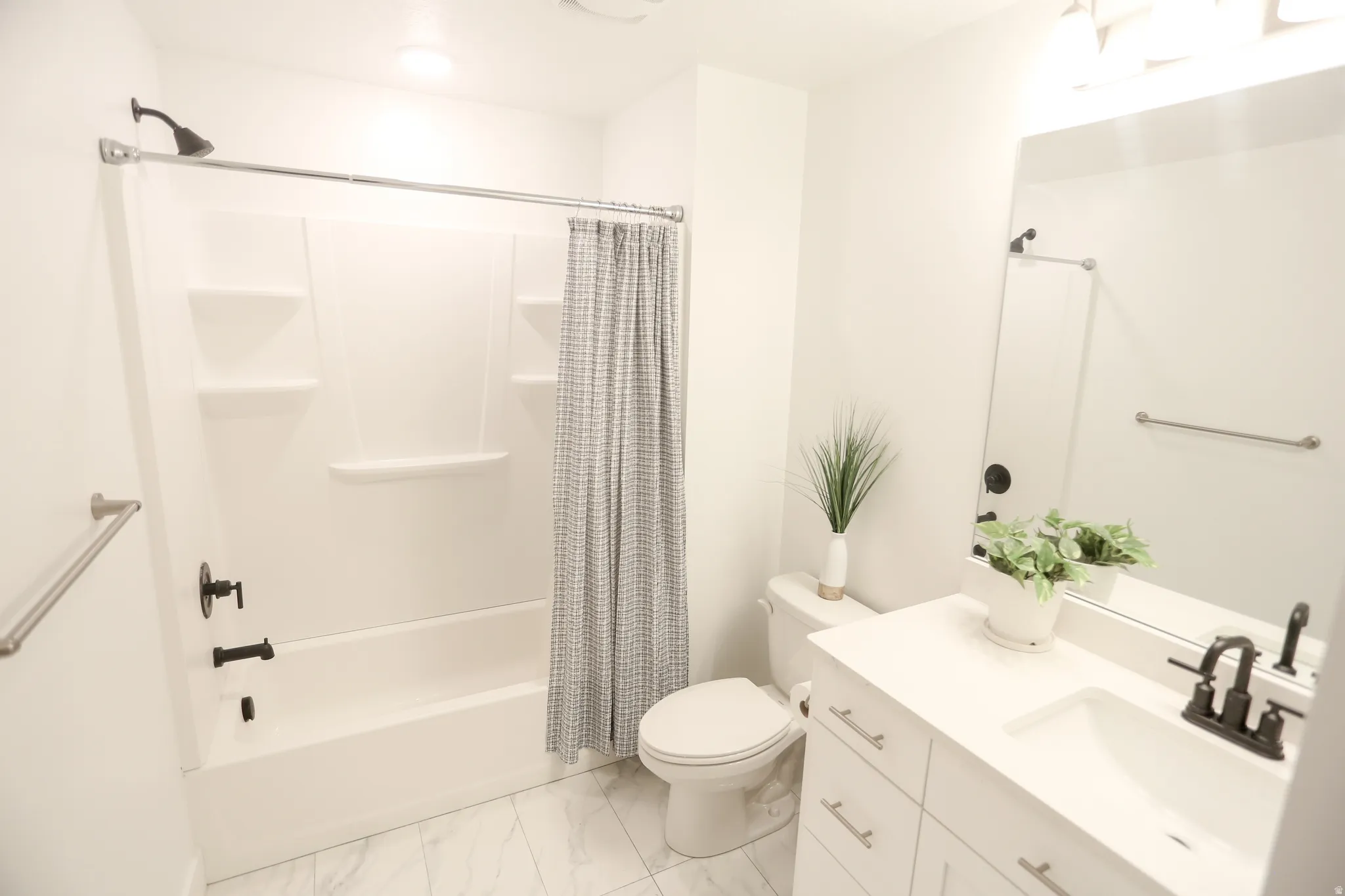 Bathroom featuring vanity, shower / bath combo, and light marble finish floors