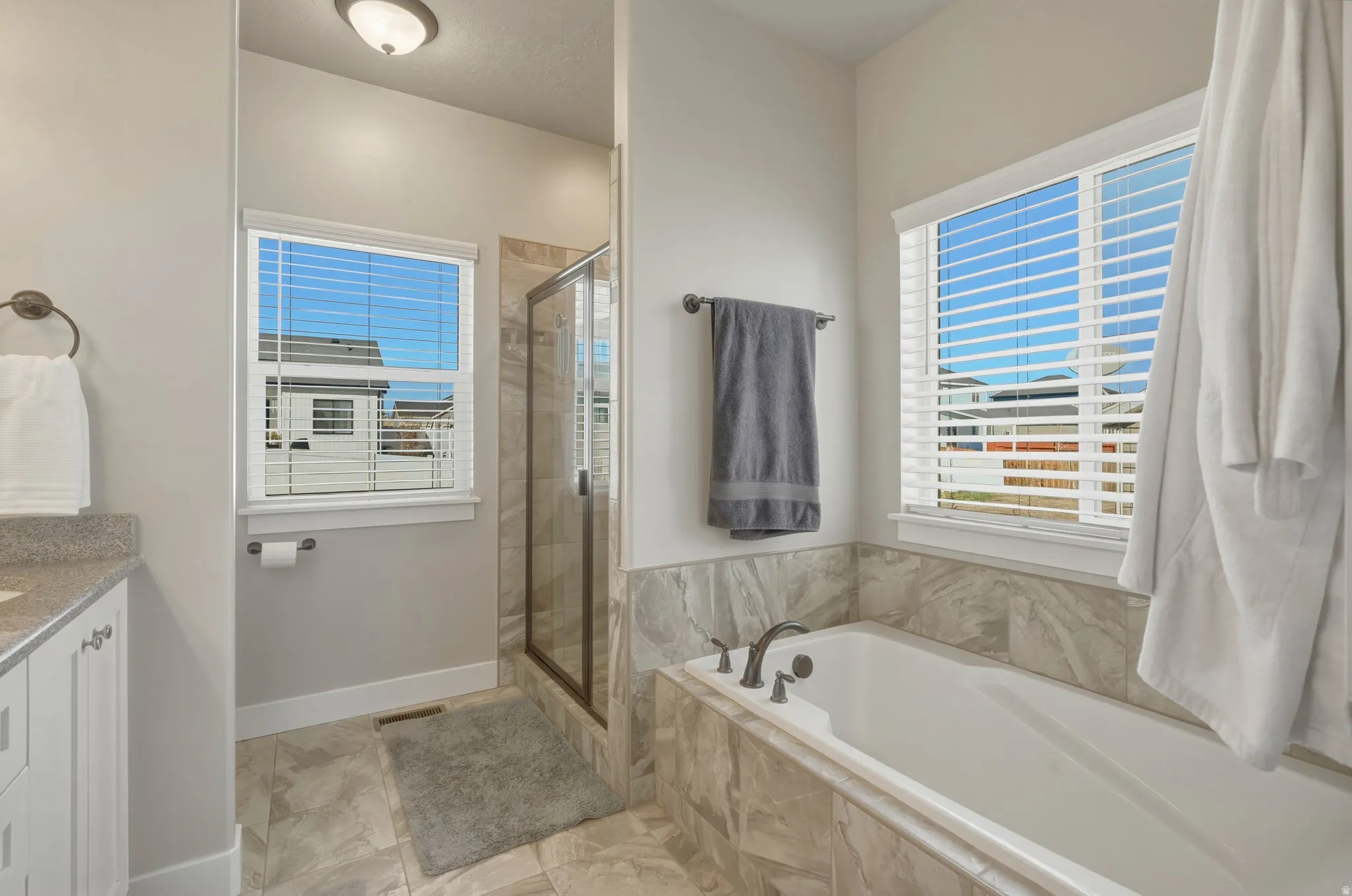 Bathroom featuring vanity, a stall shower, a garden tub, and healthy amount of natural light