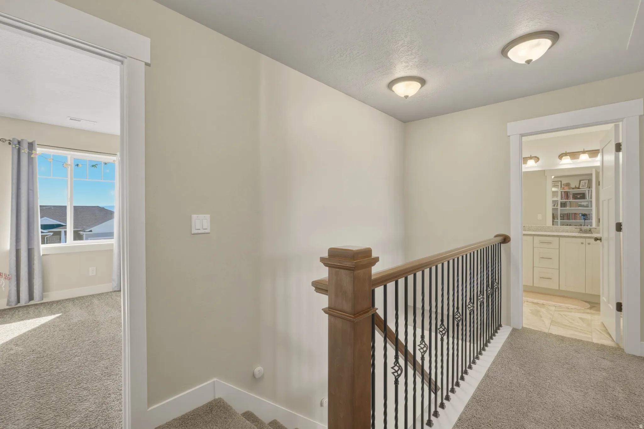 Hallway with light colored carpet and an upstairs landing