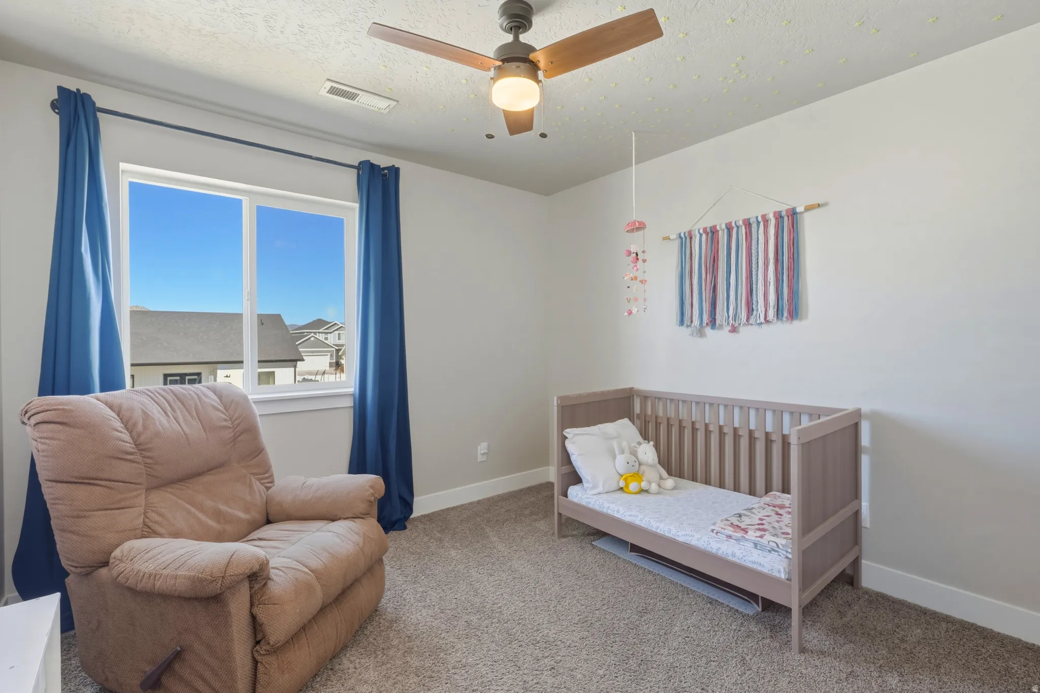 Carpeted bedroom with ceiling fan and a textured ceiling