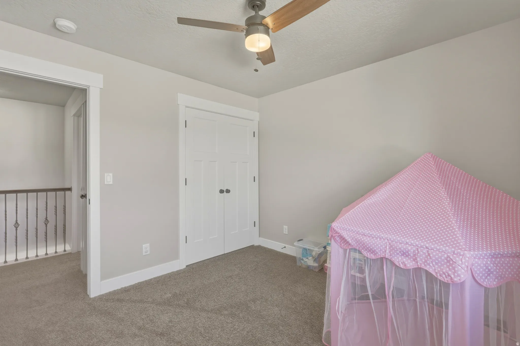 Bedroom with carpet floors, a closet, a ceiling fan, and a textured ceiling