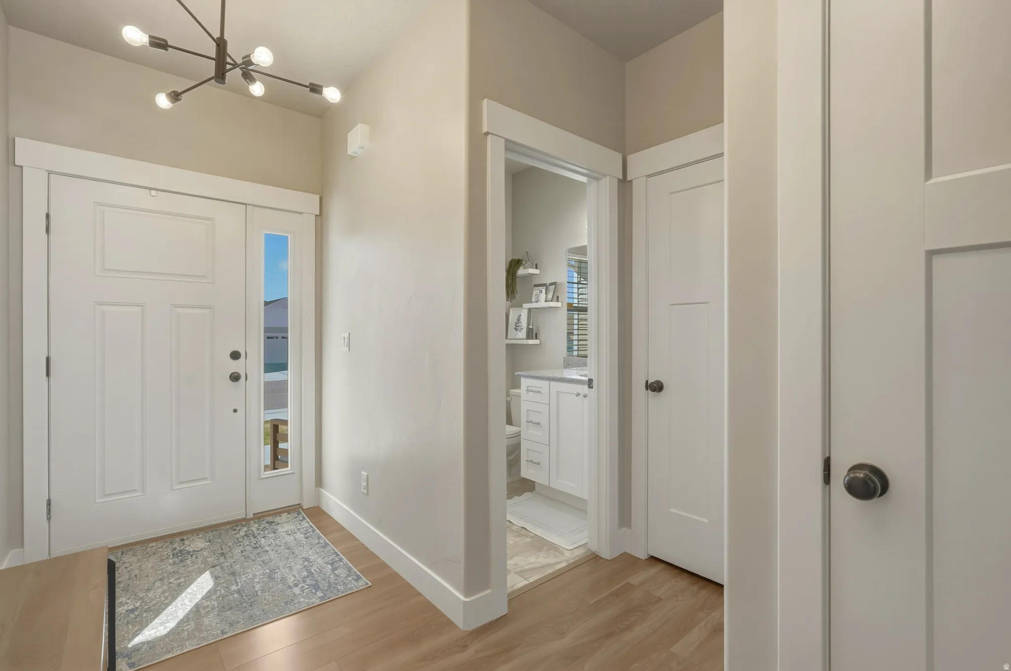 Foyer entrance with light wood-type flooring and suspended lighting