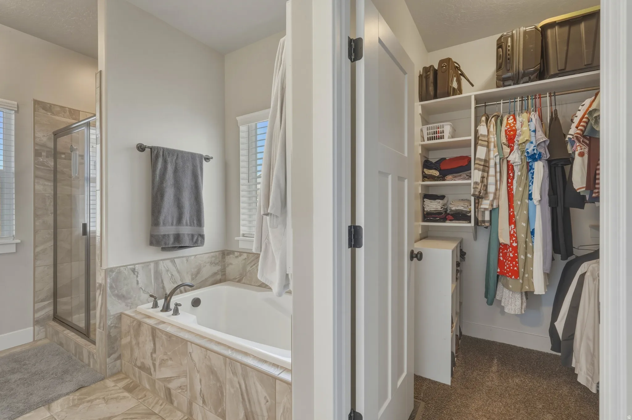 Full bathroom with a shower stall, a walk in closet, and a garden tub