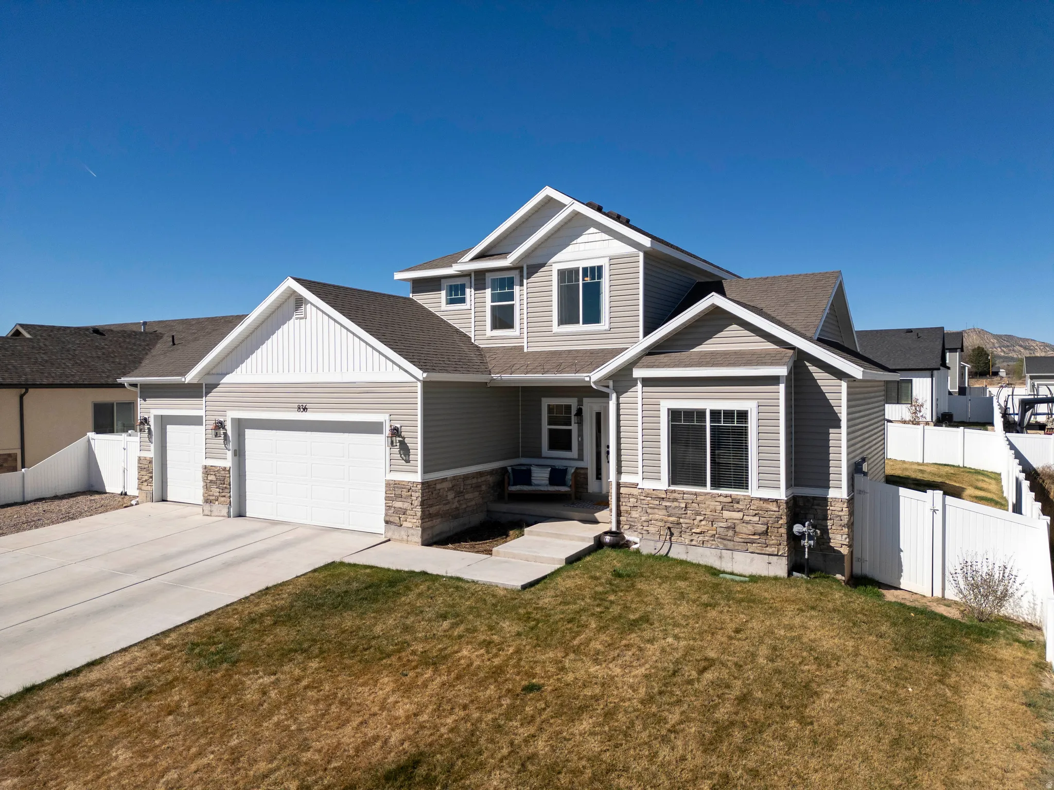 Craftsman-style home featuring stone siding, an attached garage, concrete driveway, and a gate