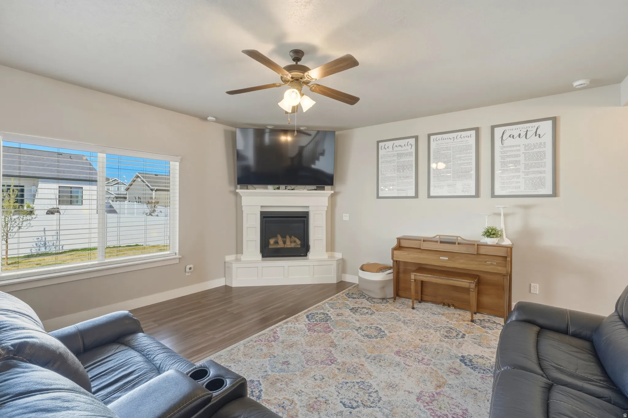 Living room featuring wood finished floors, a ceiling fan, and a glass covered fireplace