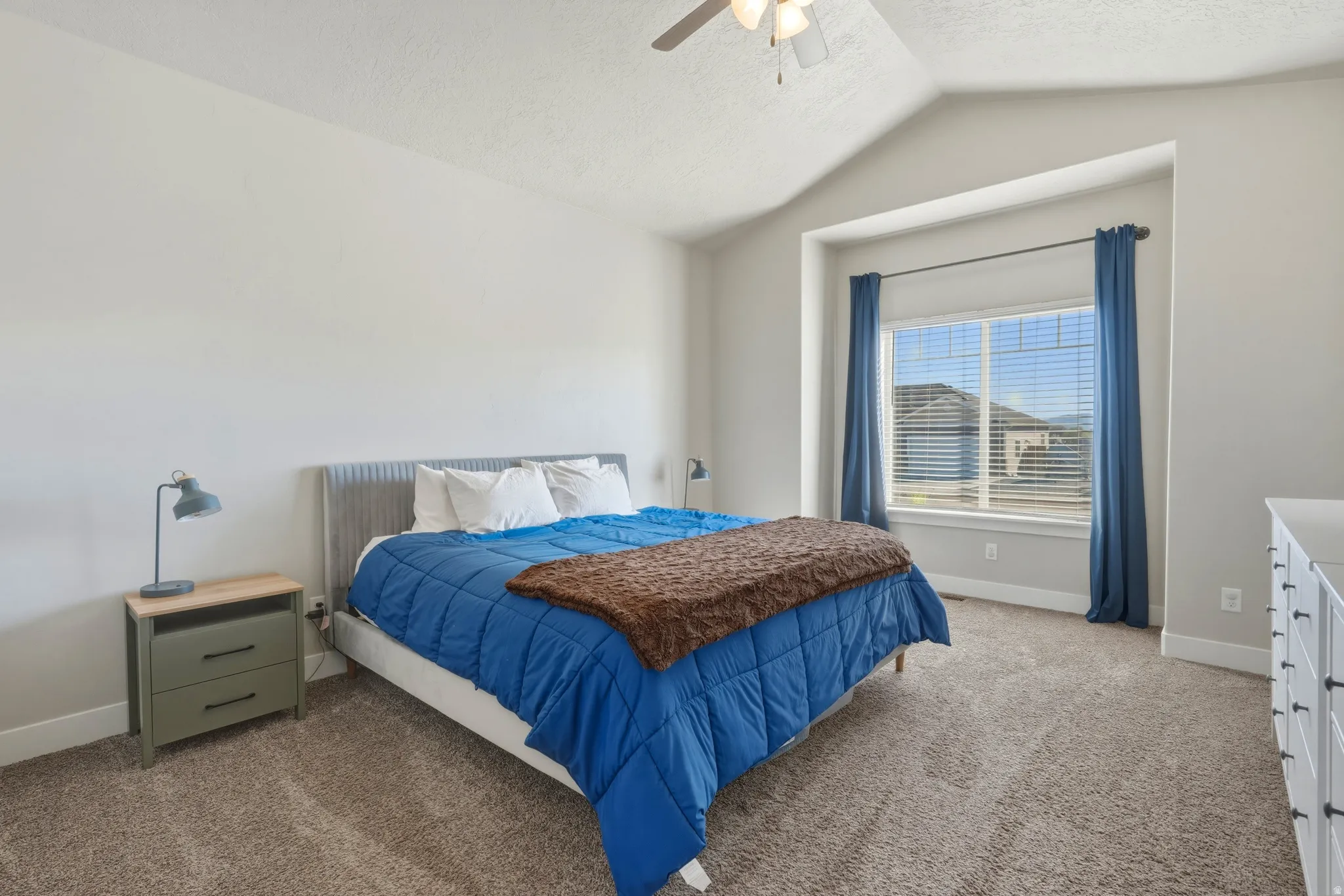 Bedroom with light colored carpet, a ceiling fan, and a textured ceiling