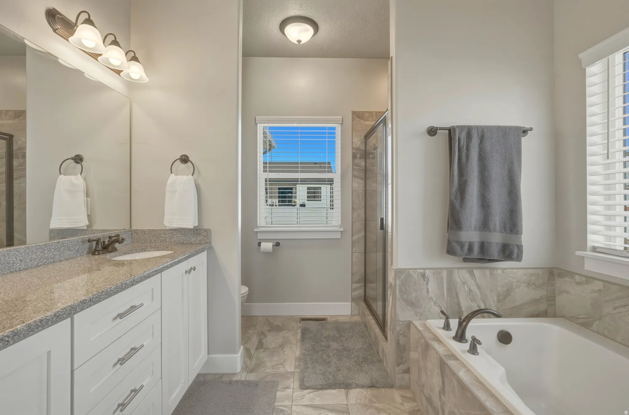 Full bath featuring vanity, a shower stall, and a garden tub