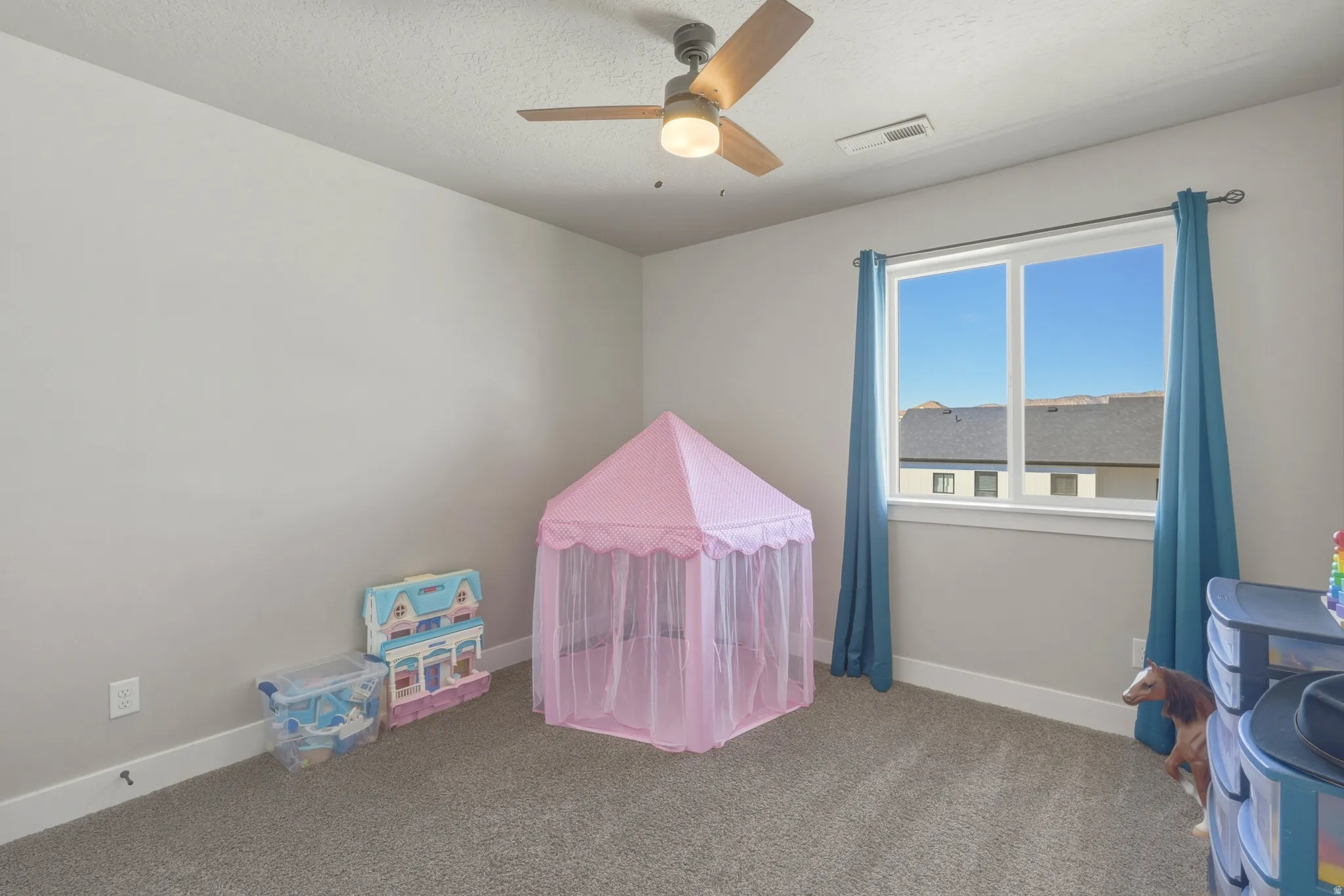 Recreation room with carpet flooring, a ceiling fan, and a textured ceiling