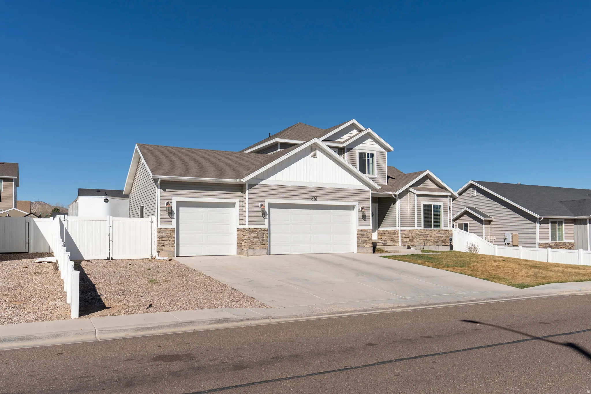 Craftsman inspired home with a gate, a garage, concrete driveway, and stone siding