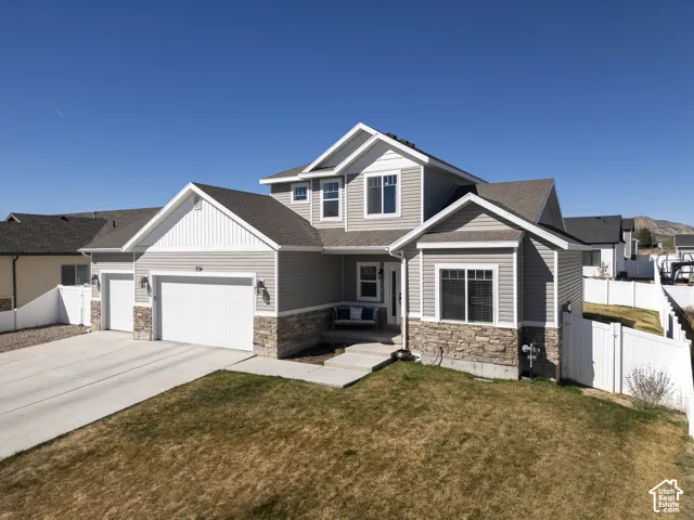Craftsman-style home featuring stone siding, an attached garage, concrete driveway, and a gate
