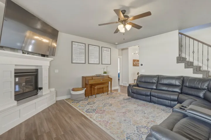 Living room with wood finished floors, a ceiling fan, and a glass covered fireplace