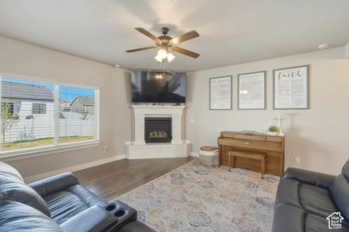 Living room featuring wood finished floors, a ceiling fan, and a glass covered fireplace