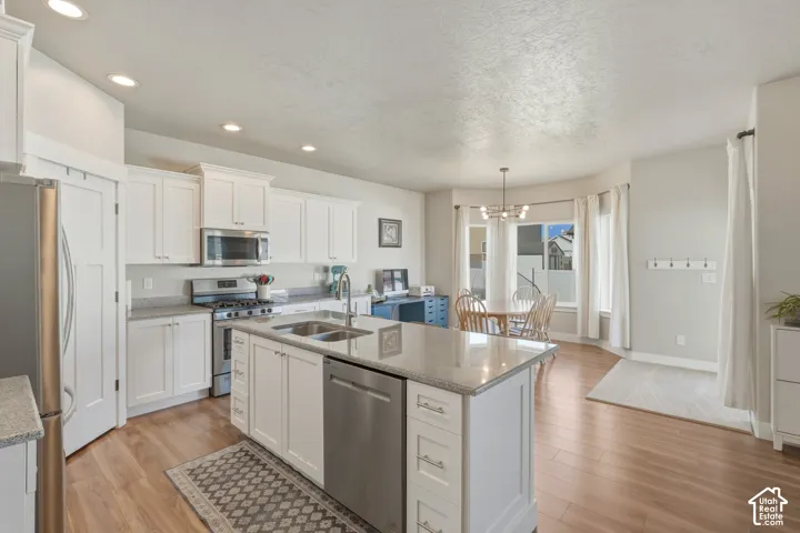 Kitchen featuring light wood-type flooring, white cabinetry, stainless steel appliances, and a textured ceiling