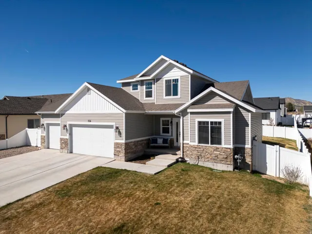Craftsman-style home featuring stone siding, an attached garage, concrete driveway, and a gate