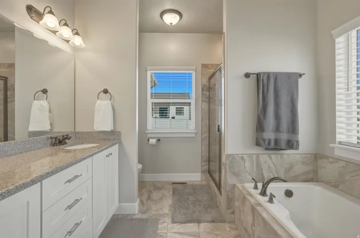 Full bath featuring vanity, a shower stall, and a garden tub