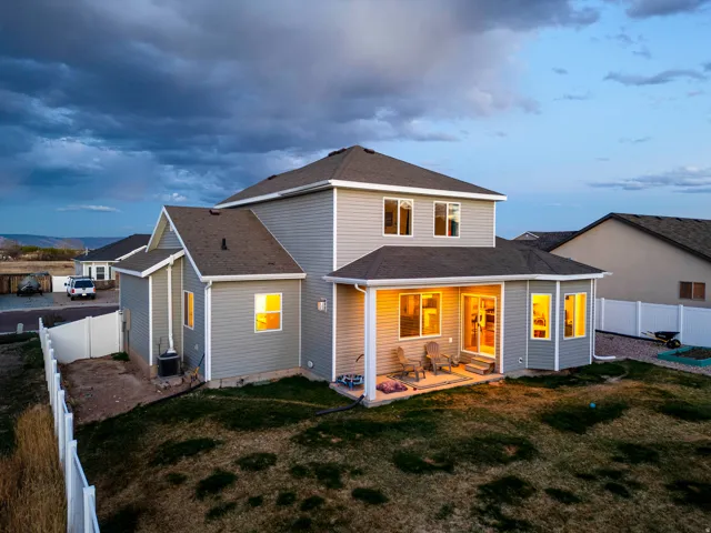 Back of house with a fenced backyard, a shingled roof, and a patio