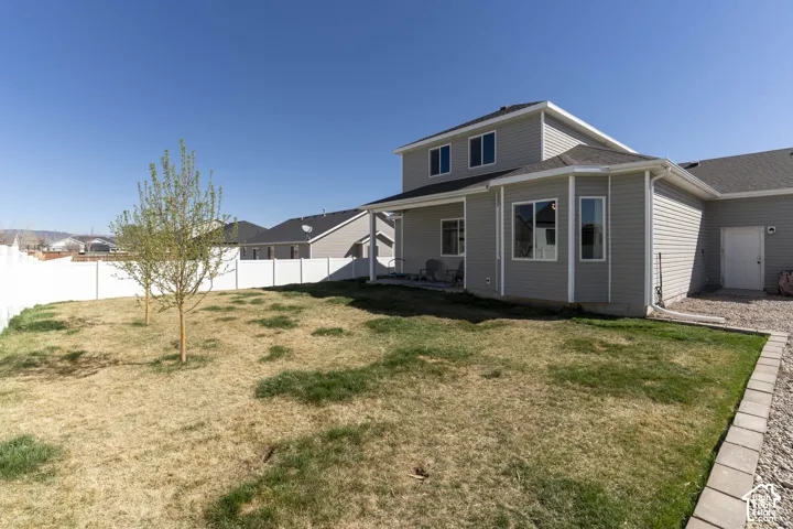 Rear view of house with a patio area, a fenced backyard, and roof with shingles