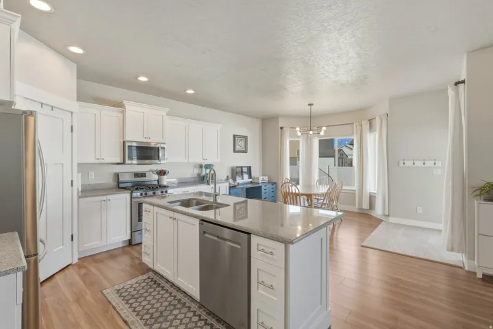 Kitchen featuring light wood-type flooring, white cabinetry, stainless steel appliances, and a textured ceiling