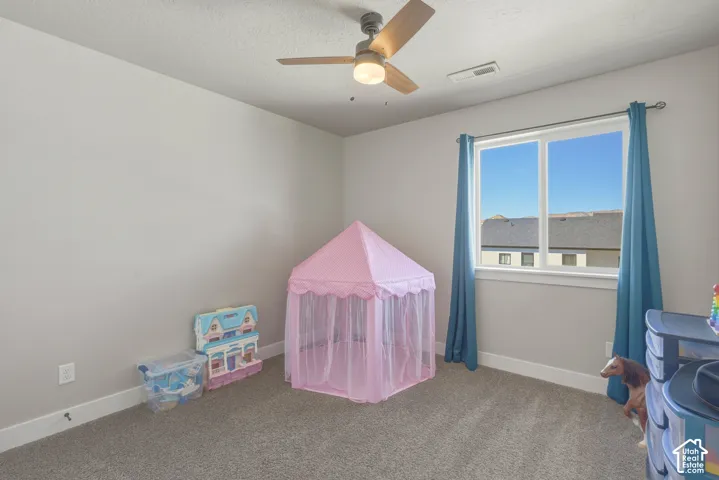 Recreation room with carpet flooring, a ceiling fan, and a textured ceiling