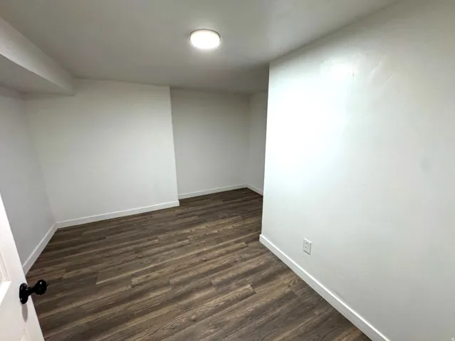 Empty room with dark wood-type flooring and baseboards