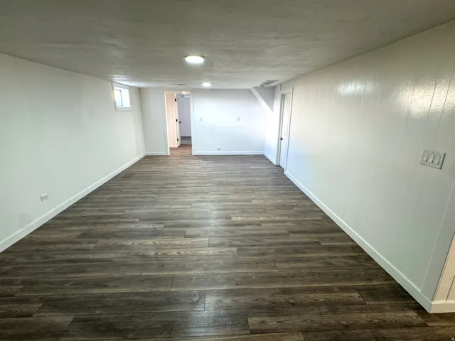 Basement with dark wood-style floors and baseboards