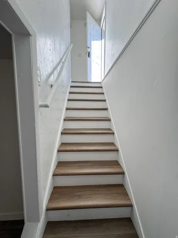 Staircase featuring a textured wall and wood finished floors