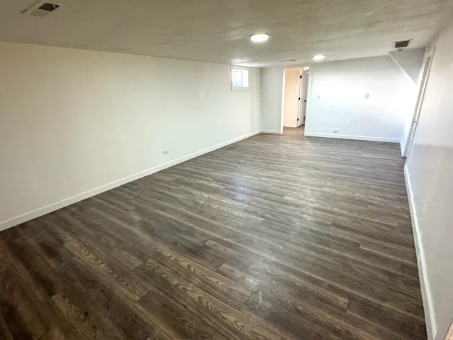 Basement with dark wood-style flooring and baseboards
