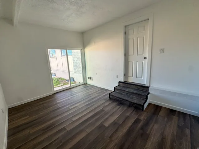 Unfurnished room featuring dark wood-type flooring and a textured ceiling