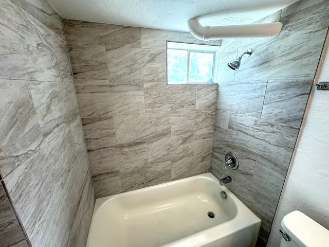 Bathroom featuring  shower combination and a textured ceiling