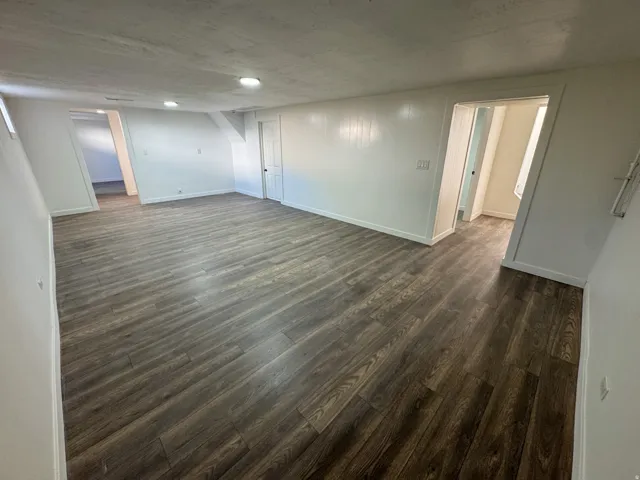 Finished below grade area with dark wood-type flooring and baseboards
