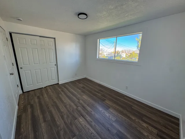 Unfurnished bedroom featuring a closet, dark wood-type flooring, and a textured ceiling