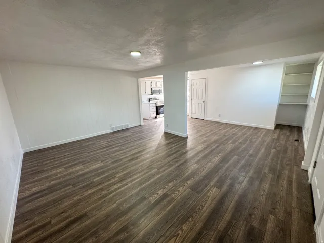 Unfurnished living room featuring dark wood-type flooring and a textured ceiling