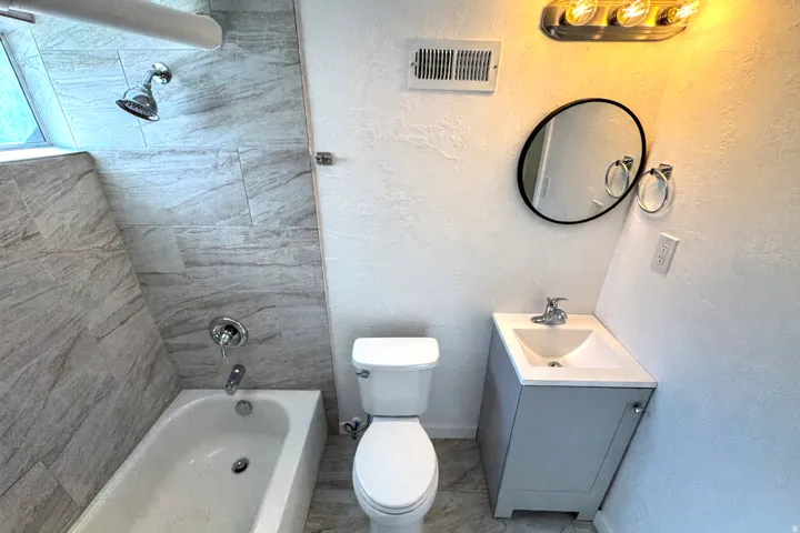 Full bath with vanity, a textured wall, and shower / bathtub combination