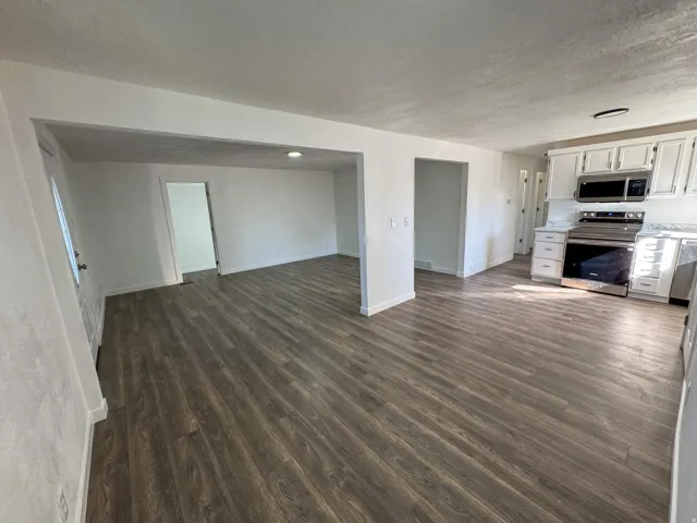 Unfurnished living room with dark wood-style floors and a textured ceiling
