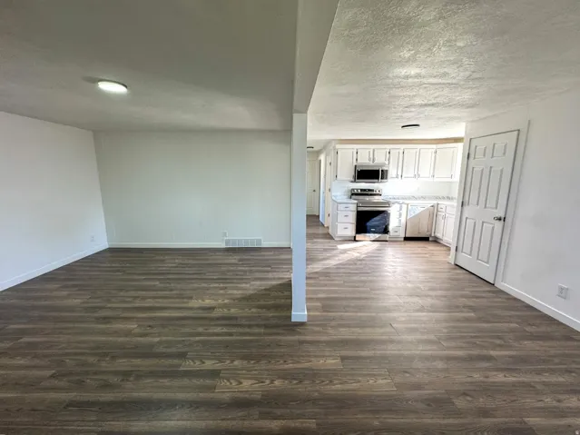 Unfurnished living room with dark wood-style floors and a textured ceiling