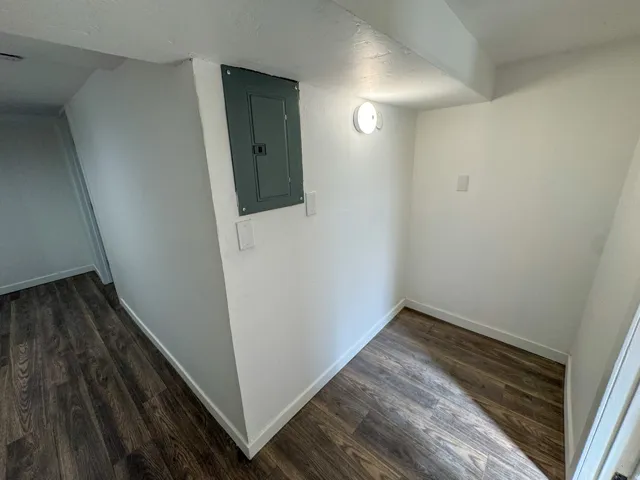 Hallway with electric panel and dark wood finished floors