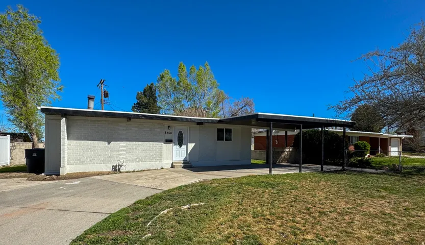 Back of property with a carport, concrete driveway, and concrete block siding