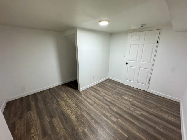 Unfurnished bedroom with dark wood-type flooring