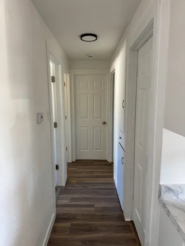 Hallway with dark wood-style flooring and baseboards