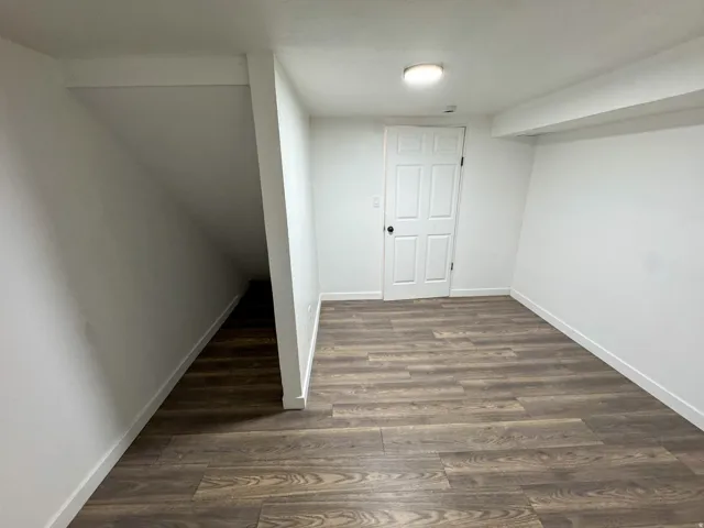Finished below grade area featuring baseboards and dark wood finished floors
