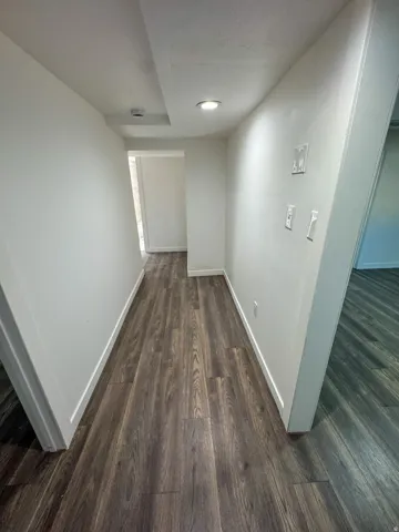 Corridor featuring dark wood finished floors