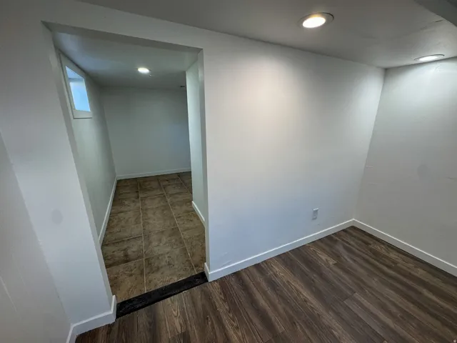 Empty room with dark wood-style floors and recessed lighting