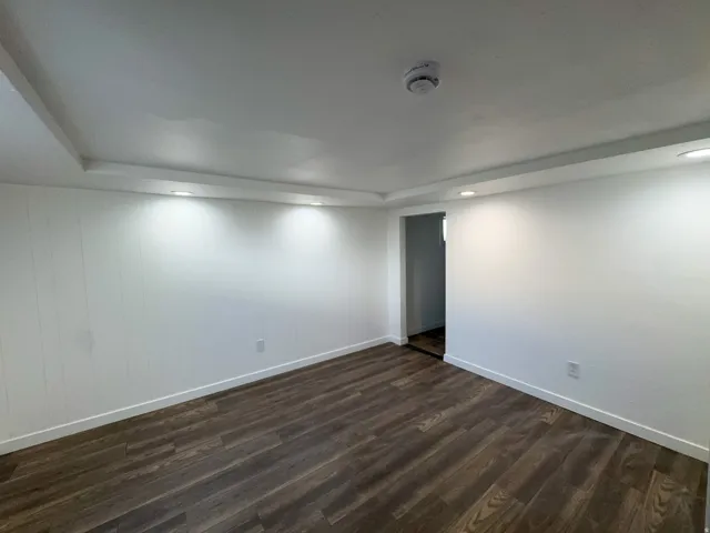 Spare room with dark wood-type flooring, recessed lighting, a smoke detector, and a raised ceiling