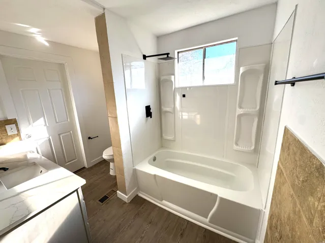Full bathroom with vanity, dark wood-style floors, and shower / bath combination