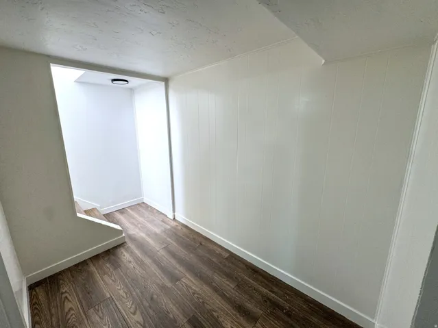 Hall featuring dark wood finished floors, a textured ceiling, and wood walls