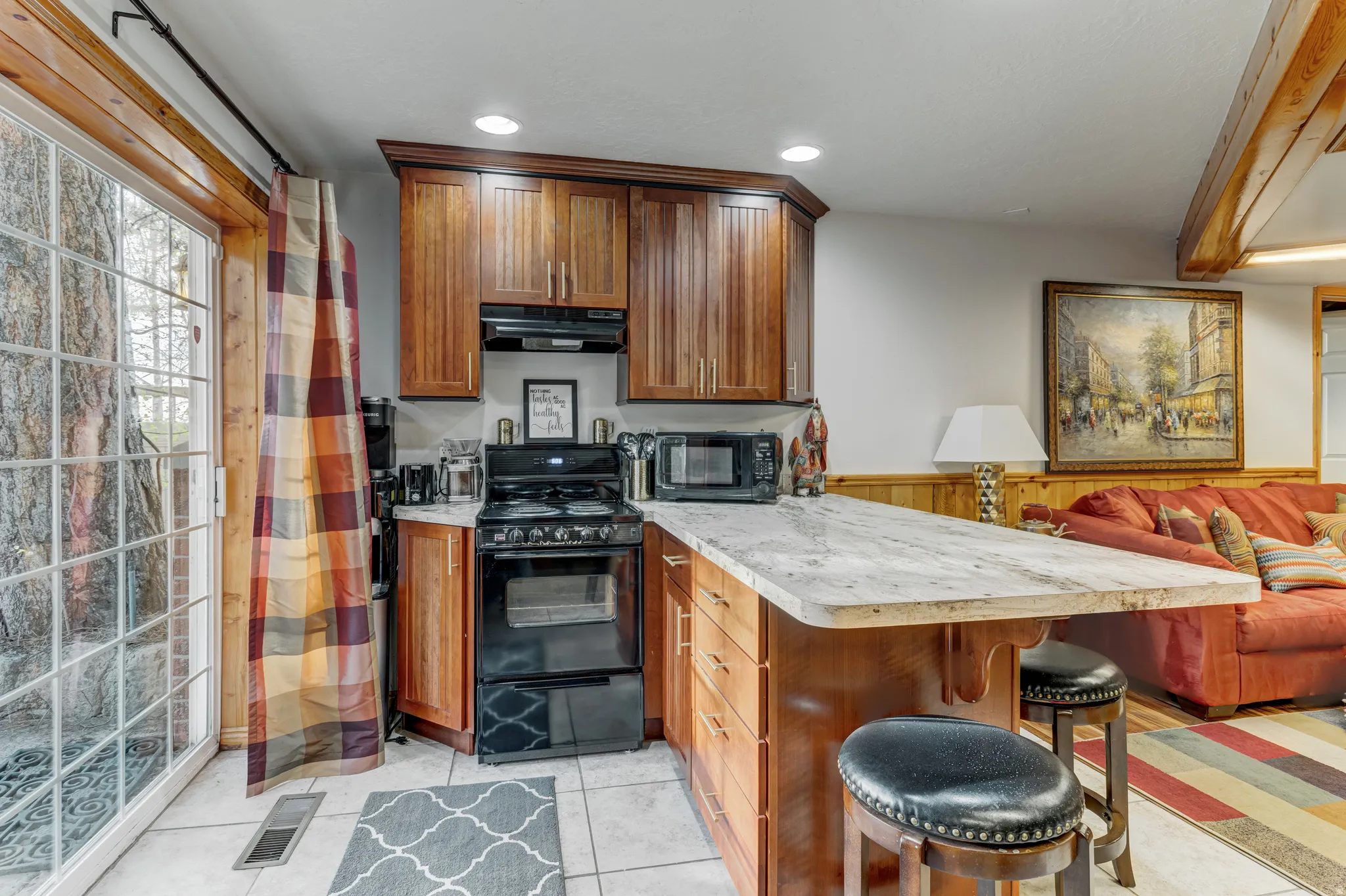 Kitchen with black appliances, light countertops, a peninsula, a kitchen breakfast bar, and wainscoting