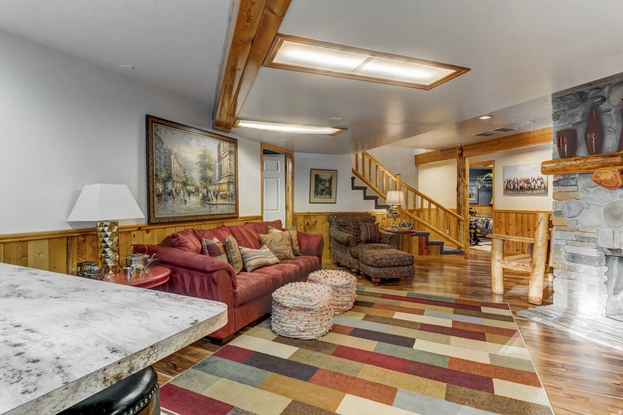 Living area with wood finished floors, wainscoting, wood walls, and a stone fireplace